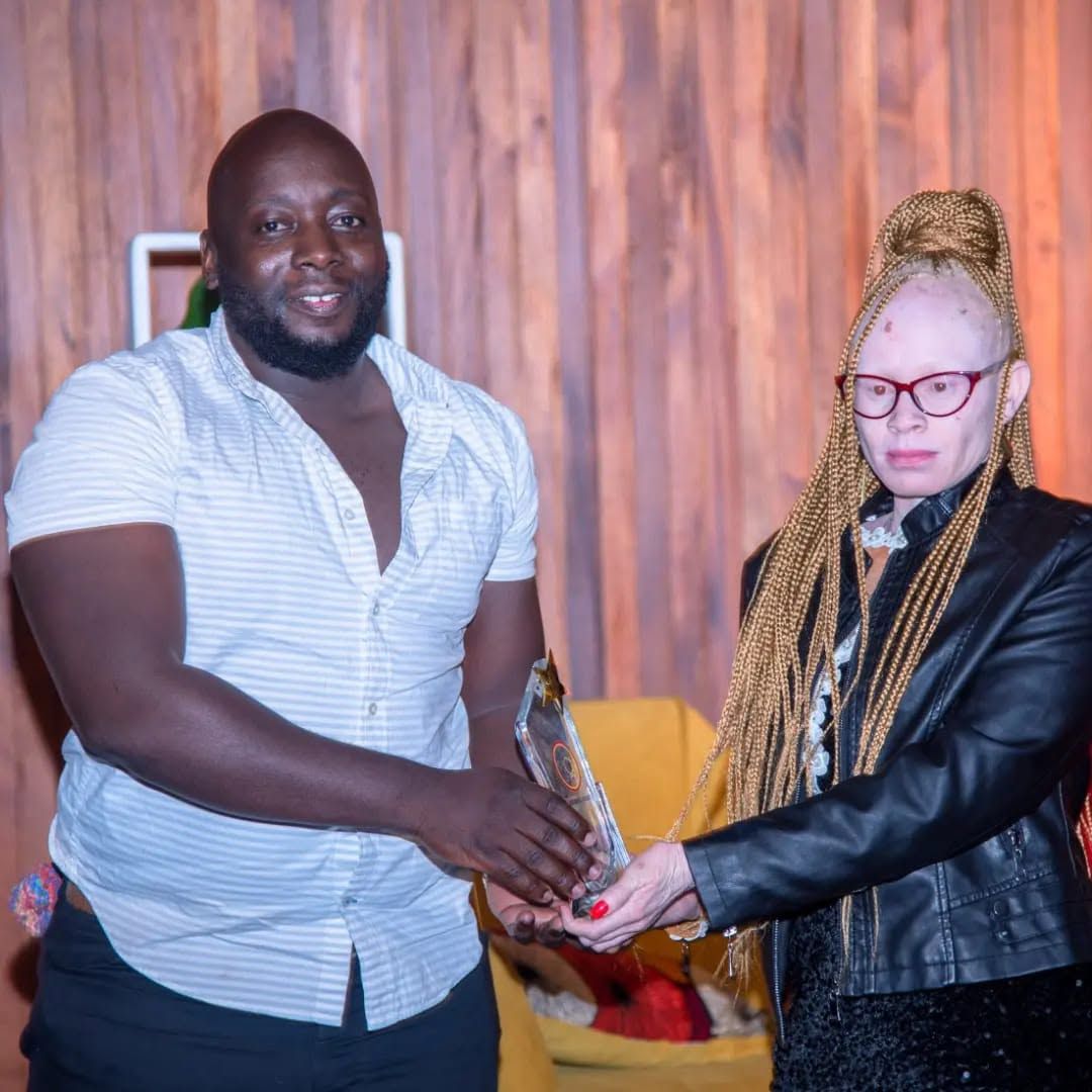 A member of the Black Albinism community receiving an award on stage.