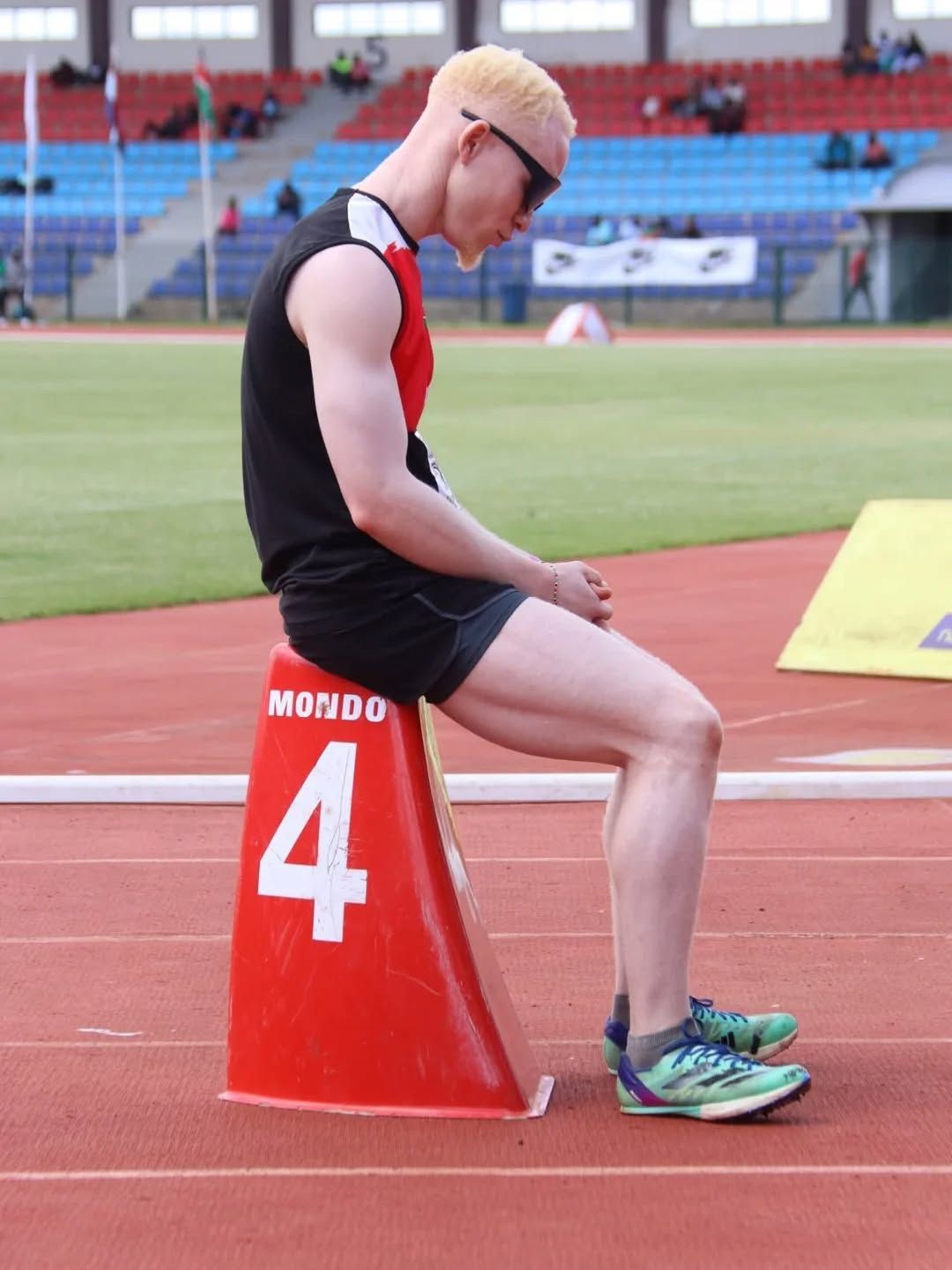 A young man with albinism in dark glasses at the track.
